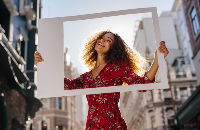 Cheerful woman smiling through polaroid picture frame