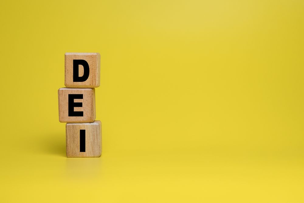 DEI or diversity equity and inclusivity words symbol on wooden blocks isolated on yellow background. copy space
