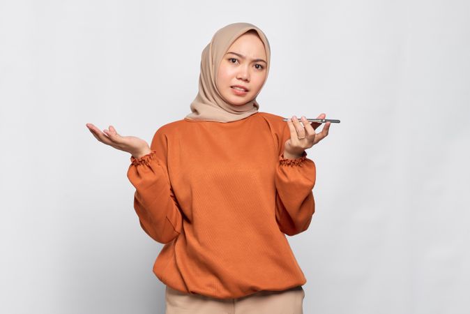 Questioning Muslim woman talking on smart phone speaker