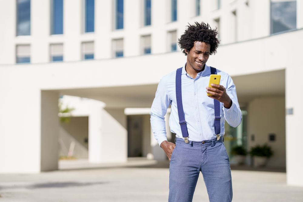 Smiling man looking at phone screen outside in the sunshine