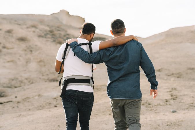 Unrecognizable diverse men walking with baby on nature