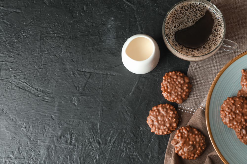 Chocolate cookies, cup of coffee and milk on dark table, space for text