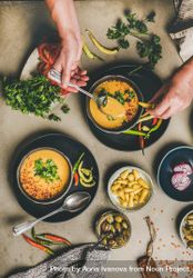 Spread of yellow lentil soup bowls, vegetable garnishes with man with spoon in soup 5lgD60