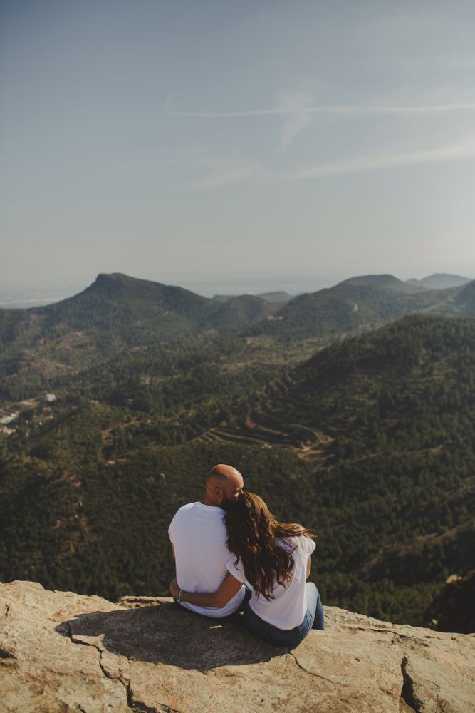 Happy couple sitting at mountain cliff