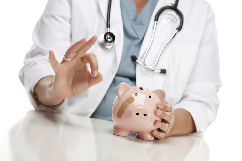 Doctor Gives Okay Sign Behind Piggy Bank
