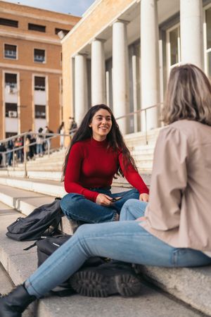Two students sitting on the stairs of the college