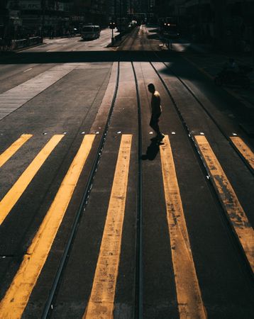 Silhouette of a man walking on pedestrian lane