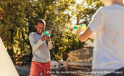 Two kids playing with water guns in backyard 43vEx5