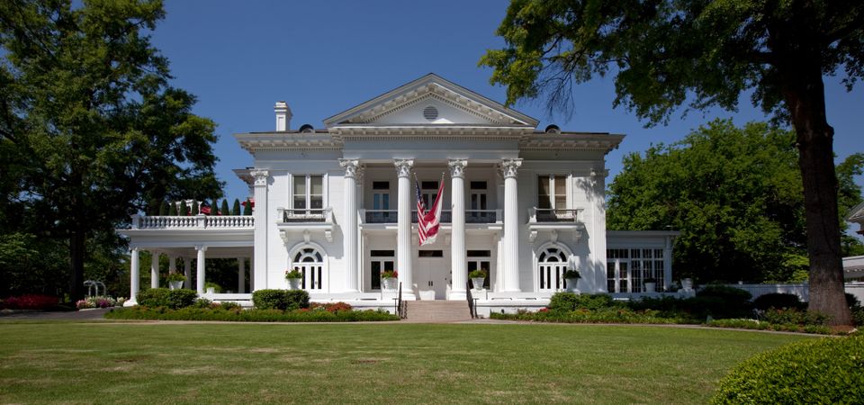 Front view of the Alabama Governor’s Mansion with flags and cream facade