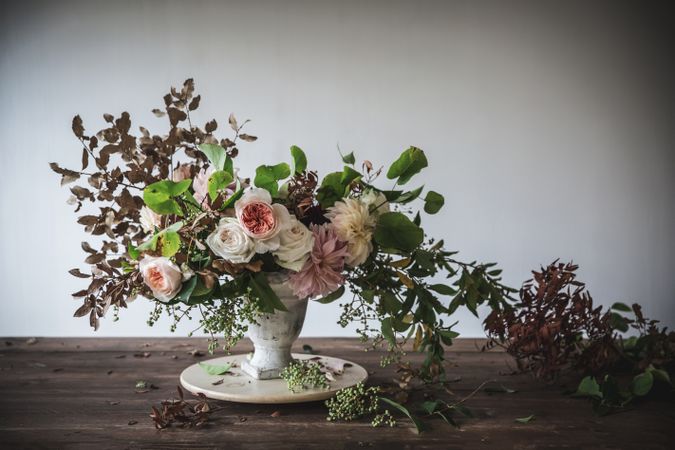 Composition of flowers and plants in vintage vase on board