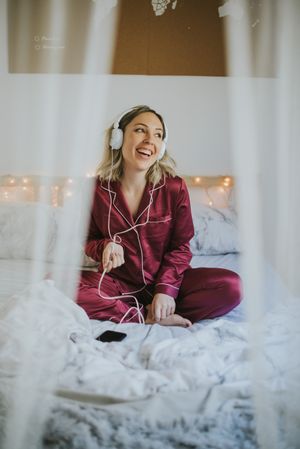 Woman with headphones dancing in bed