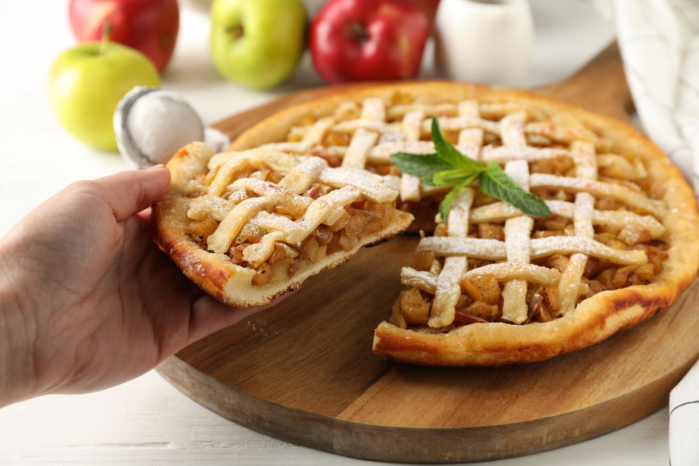 Female hand holding piece of apple pie. Homemade food