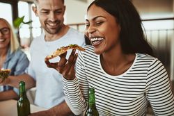 Woman enjoying a slice of pizza in a bright modern office