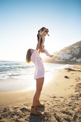 Woman holds up dog on beach