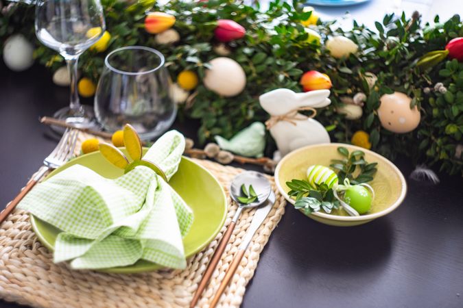 Easter table setting with rabbit napkin ring on pastel green napkin and decorative eggs