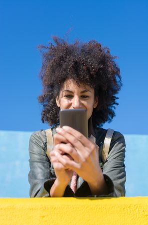 Black woman with afro hair leaning against brightly colored wall
