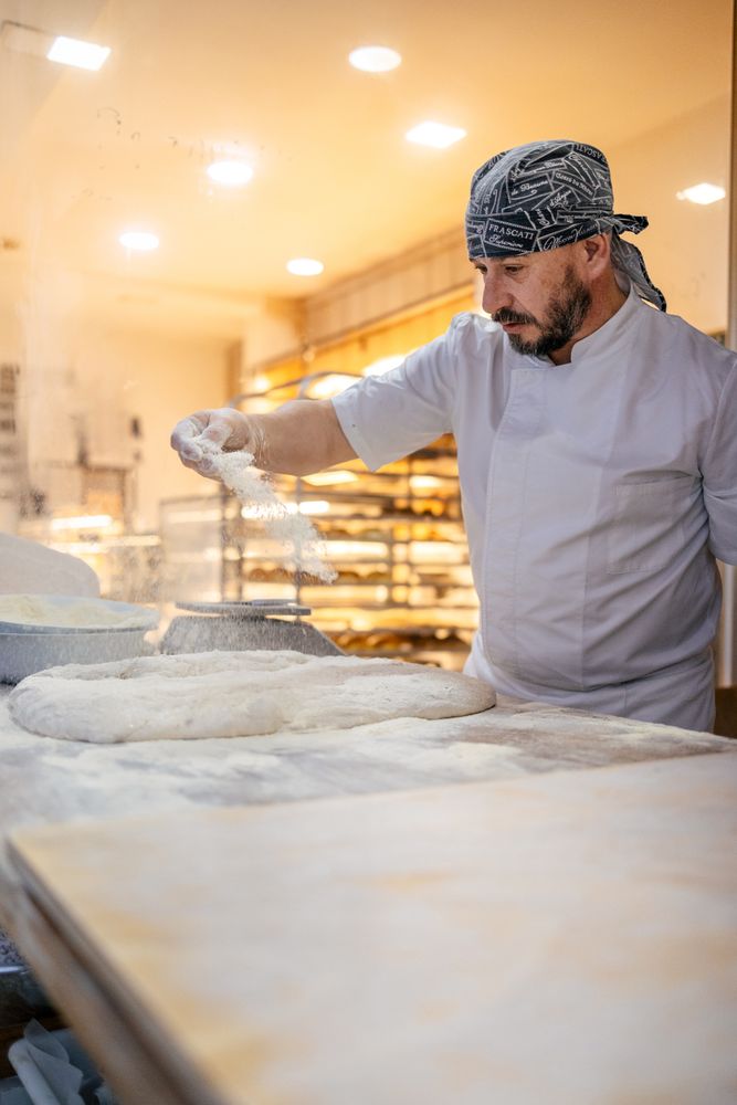 Baker pouring flour on the dough