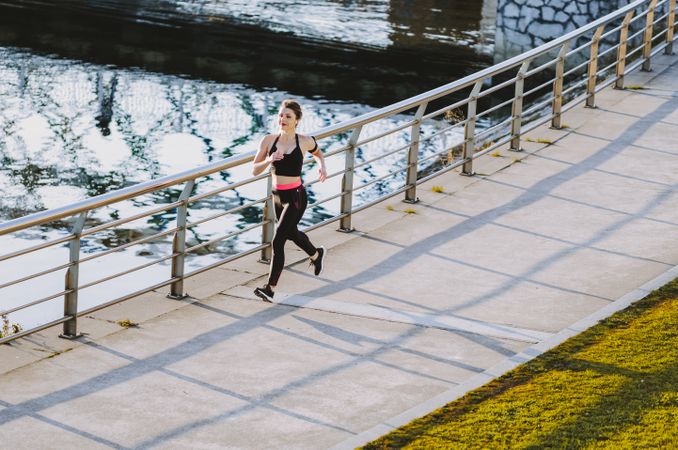 Woman running on embankment near water