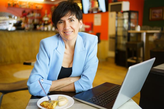 Portrait of woman in cafe with laptop and slice and cake