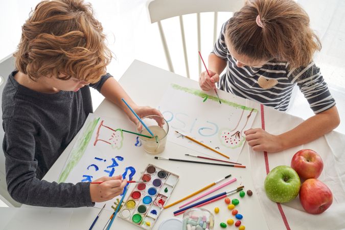 Children drawing on paper sitting at table