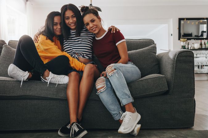 Teenager girls sitting together holding each other on couch