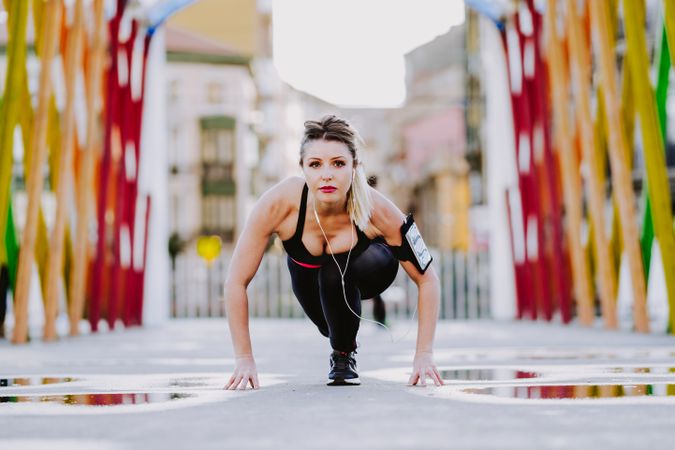 Woman with earphones stretching legs on street
