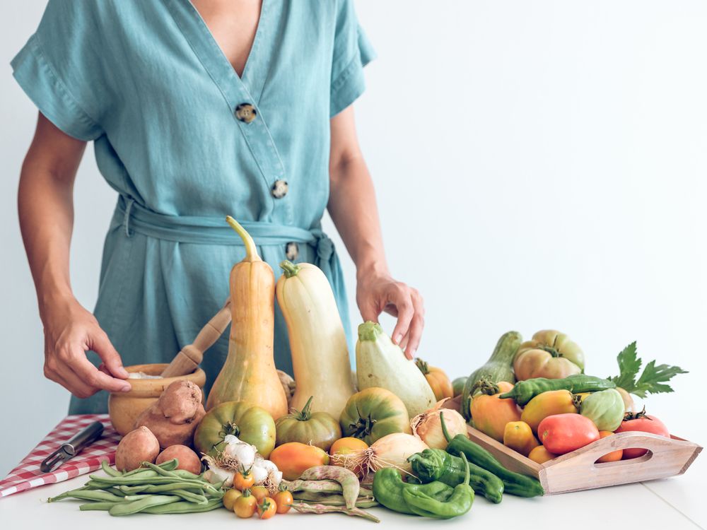 Anonymous woman with pile of fresh vegetables
