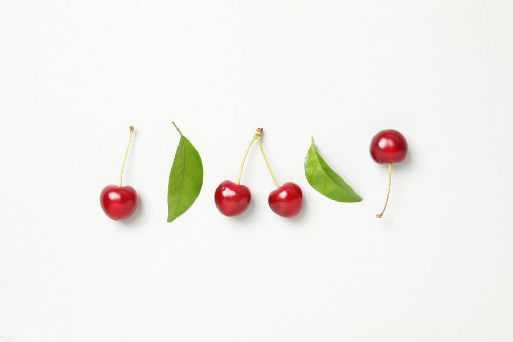 Ripe juicy cherry fruits with leaves on a light background
