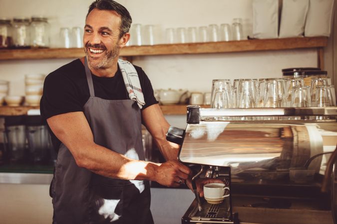 Handsome man enjoying making coffee for his customers