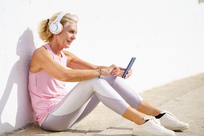 Mature female in athletic wear texting on pier