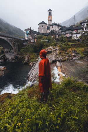 Back view of person wearing red rain coat standing near village