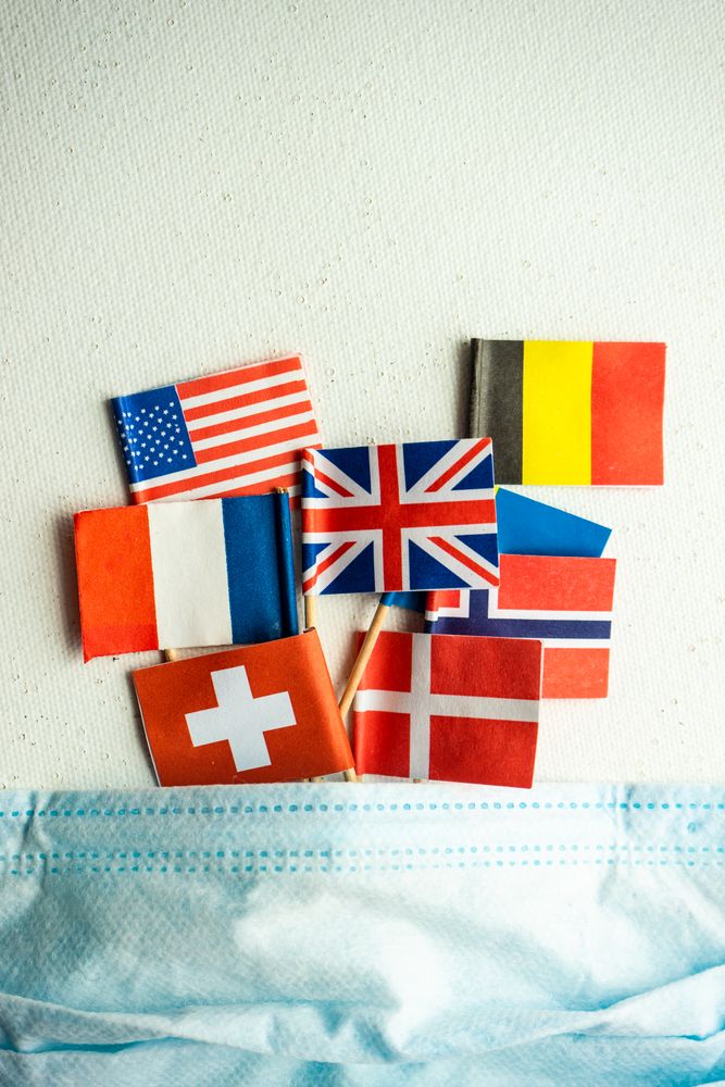 COVID-19 concept  with face mask and flags of countries emerging