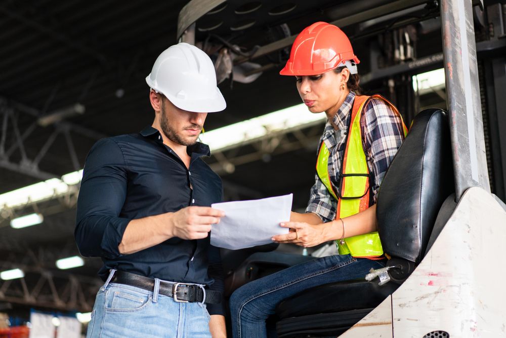 Two colleagues going through itemized list in distribution center