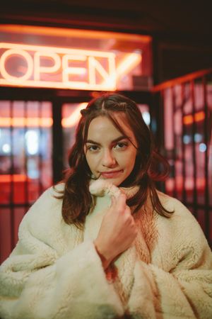 Beautiful young woman wearing fur coat standing outdoors
