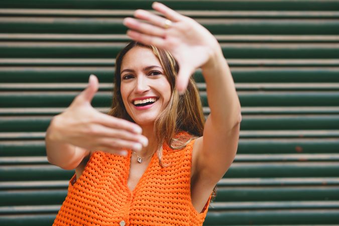 Woman smiling at camera framing her face with hands