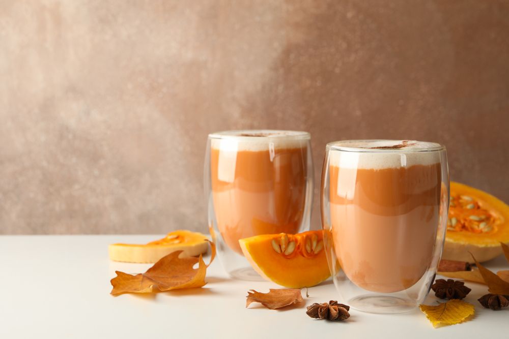 Composition with pumpkin latte, cinnamon, leaves and pumpkin on wooden table