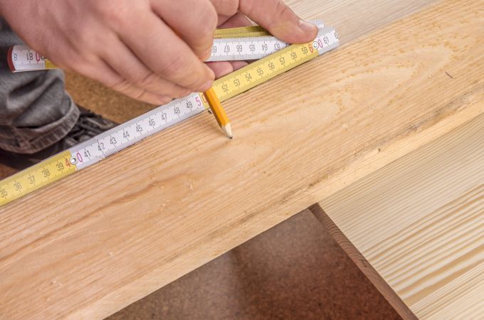 Carpenters hands measuring a wooden board