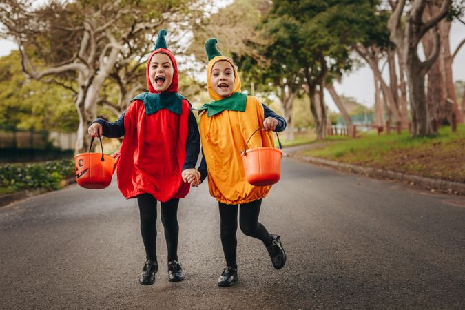 Cute little girls in halloween costume trick or treating outdoors