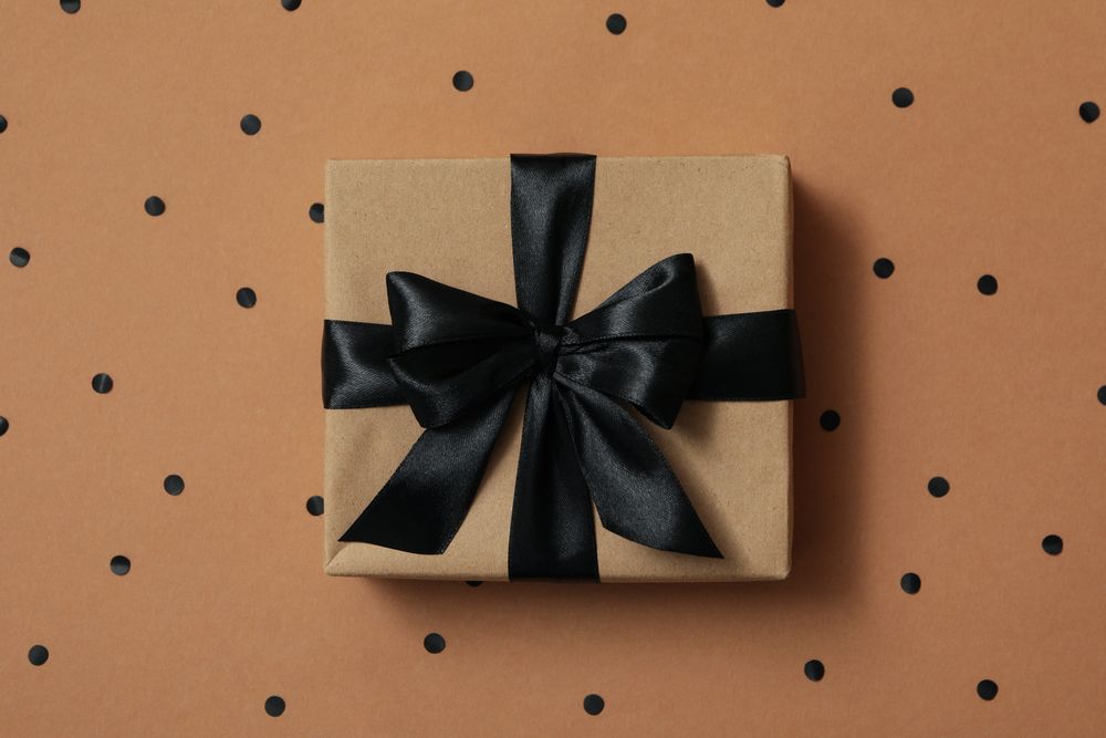 Gift box with dark bow on craft background