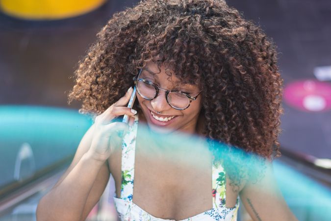Glad woman speaking on smartphone in park