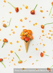 Waffle cone with orange buttercup flowers on a light background, vertical composition beglE5