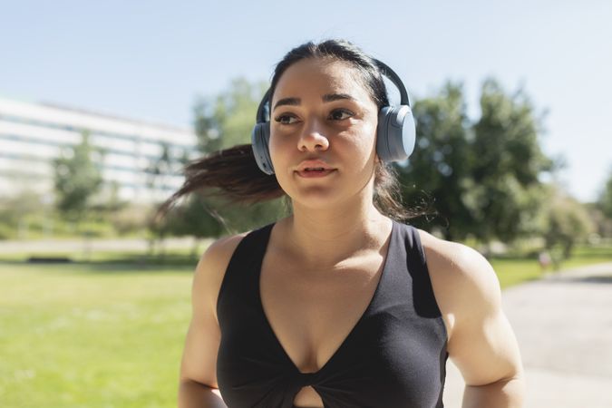 A young woman listening to music with headphones, while she is running and training, Zaragoza, Spain