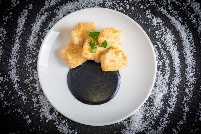 Hake breaded with squid cream in plate