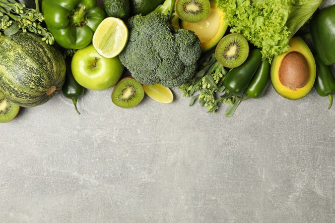 Green fruits and vegetables on gray background, space for text
