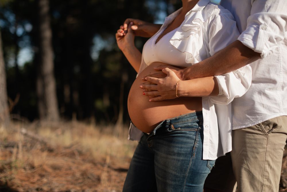 Close-up portrait of a pregnant woman holding hands and being embraced by her husband