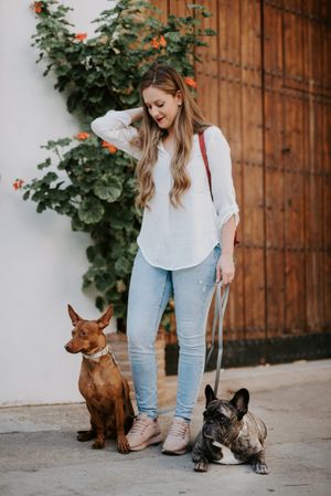 Stylish woman with dogs standing on street