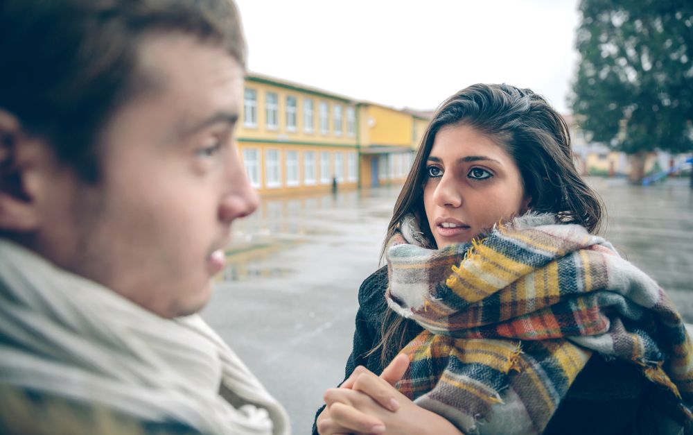 Woman approaching man outside on cold autumn day