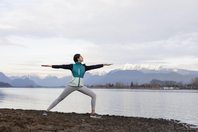 Young woman practicing yoga on the lake shore