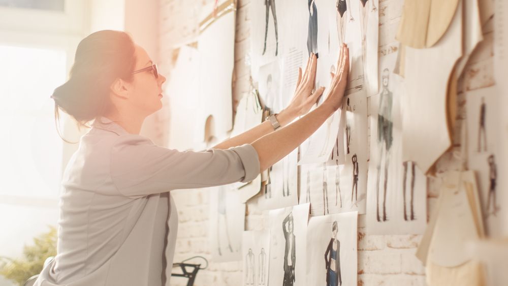 Female fashion, designer,  Choosing Sketches for Her Project and Pinning them to the Wall.