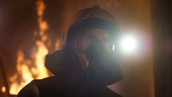Portrait of a firefighter with mask and fire behind
